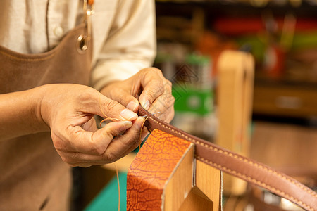 中年男性皮匠手工缝制皮带细节背景
