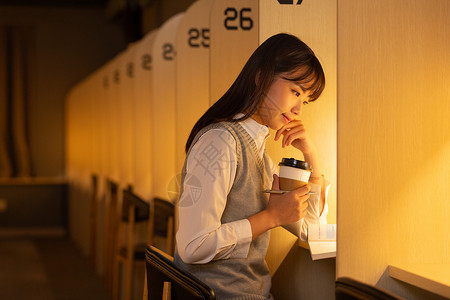 女大学生手捧咖啡杯自习室认真学习图片