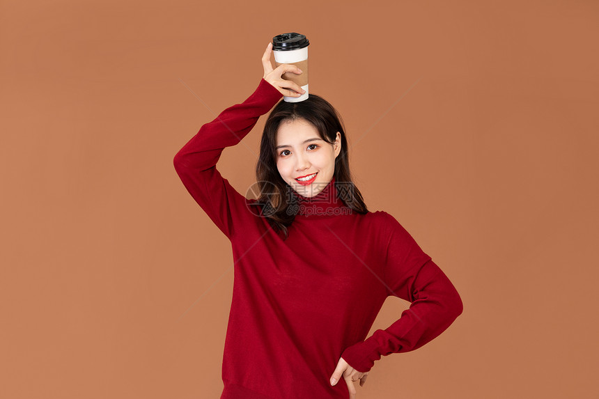穿红色毛衣的女性手捧咖啡杯图片