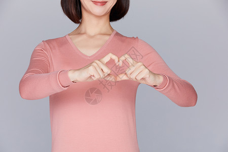 关爱女性胸部健康女性在胸口比划爱心背景图片