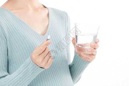 孕期保健年轻女性孕妇拿着水杯准备吃药背景