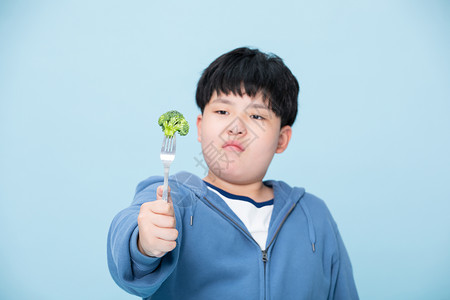 拿着花菜犹豫的男孩挑食的人背景图片