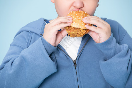 高热量汉堡小男孩大口吃汉堡肥胖的男孩特写背景