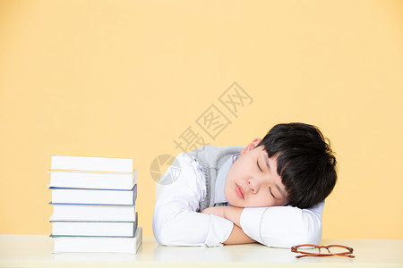 小男孩在课桌上休息趴桌上打瞌睡背景图片