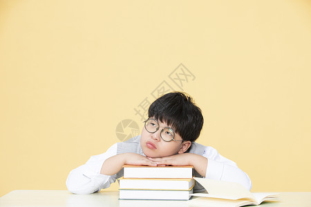 书上的眼镜小男孩趴在书上小男孩发呆背景