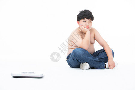 男孩坐在体重秤旁边心情失落肥胖图片