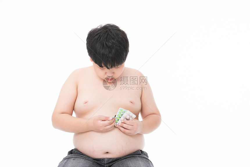 生病的小男孩小胖子低头看药图片