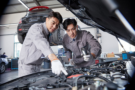 修理工人汽车修理工在检查发动机两人检查汽车背景