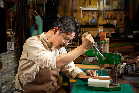 皮具缝纫男性皮匠给真皮鞋垫打孔背景