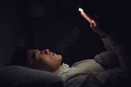 熬夜失眠年轻男士深夜躺在床上玩手机背景