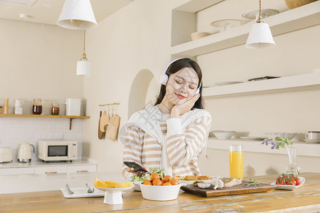 头戴耳机听音乐的女孩享受午餐高清图片