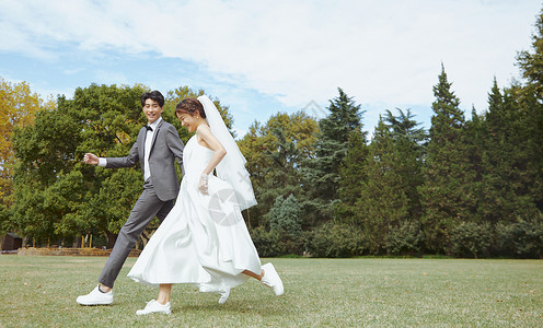 亚洲新娘在草坪上牵手奔跑的情侣背景