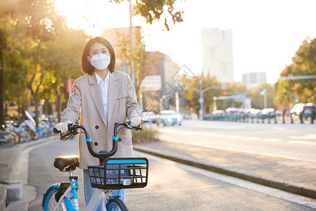 细菌病菌佩戴口罩与手套的都市女性骑共享单车背景