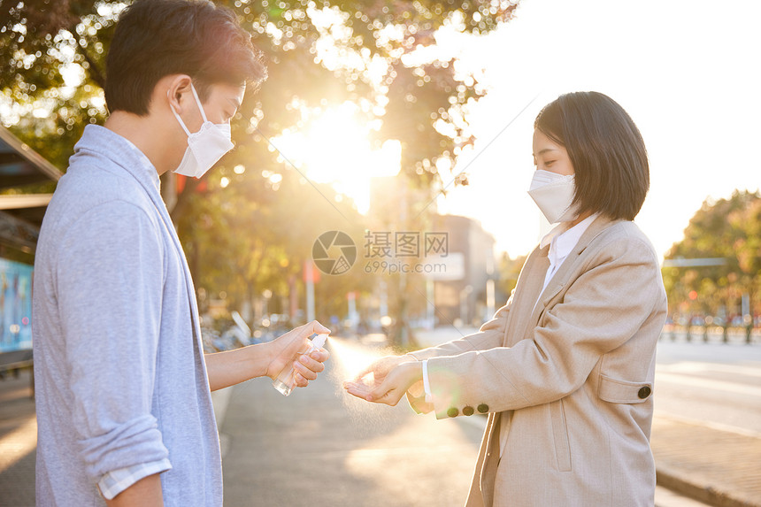 户外使用酒精喷雾消毒除菌的青年情侣图片