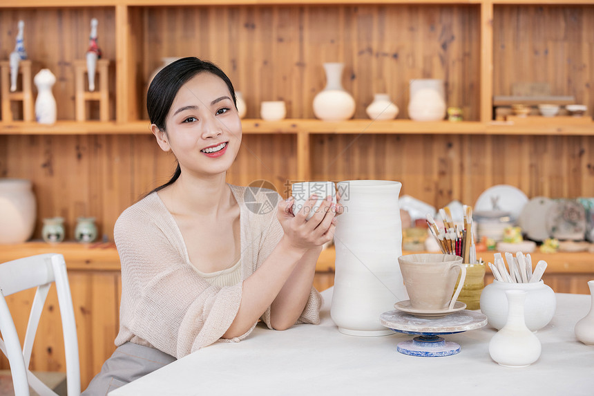 美女陶艺匠人展示陶艺品图片