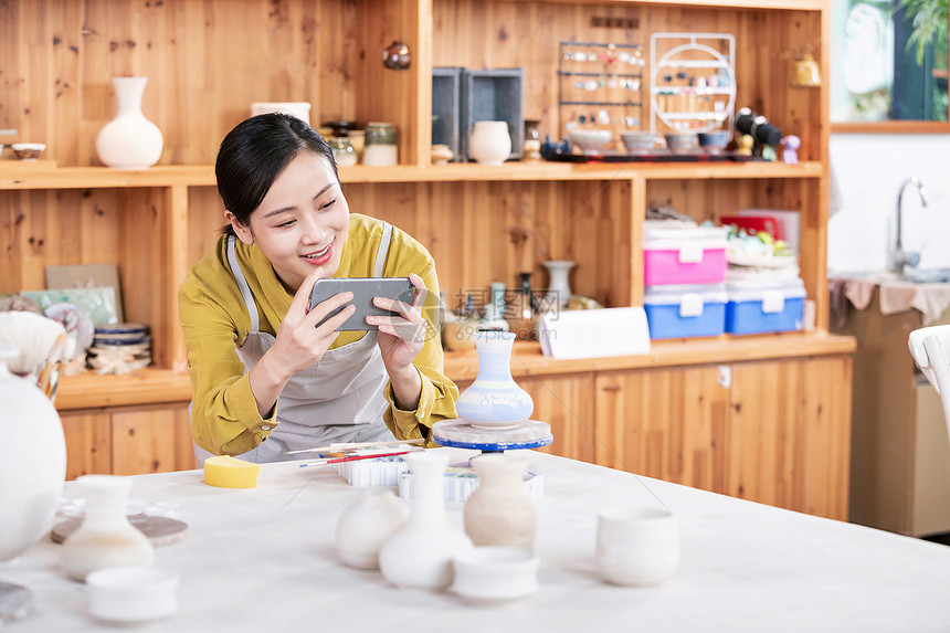 美女拿手机拍摄陶艺半成品图片