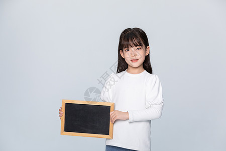小女孩拿着小黑板在身侧背景图片