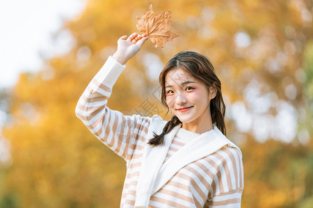 手拿树叶的秋季可爱女孩高清图片
