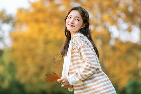 手拿树叶的秋季可爱女孩背景图片