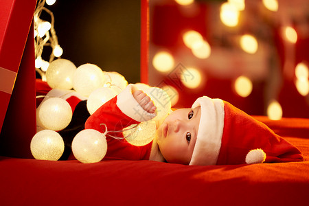 圣诞帽礼物盒躺在礼物盒里的圣诞宝宝背景