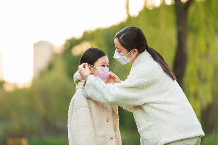 妈妈在公园帮女儿调整口罩图片