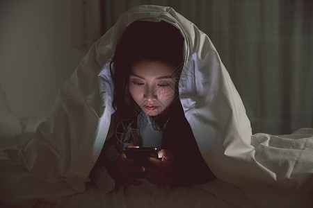 青年女性被窝里自熬夜玩手机游戏高清图片