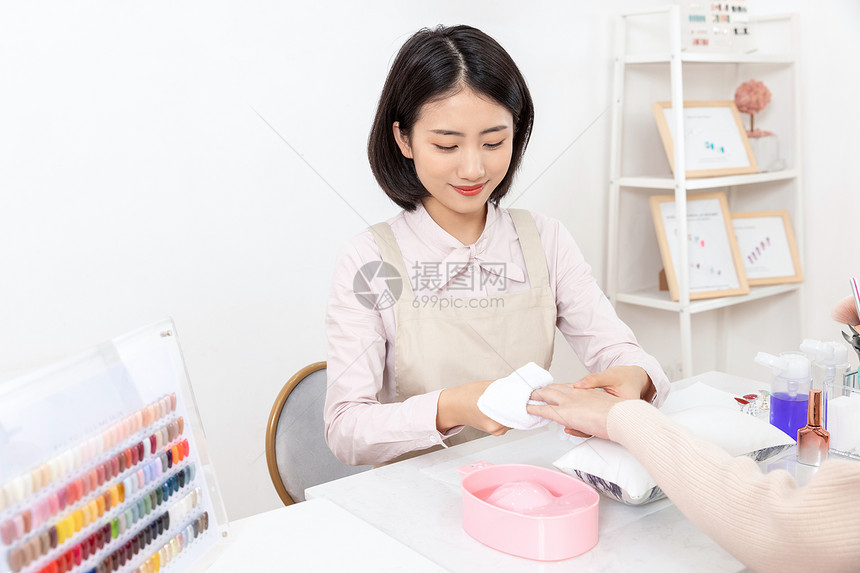 女性美甲师帮美女顾客清洁指甲图片