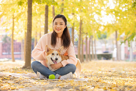 抱着球的狗女性抱着宠物坐在地上背景