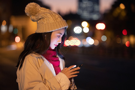 戴帽子神秘人冬季夜晚美女路边等候看手机背景