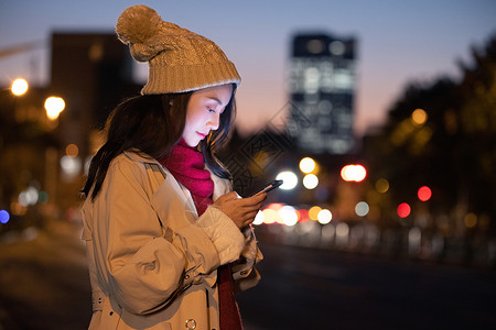 冬季夜晚美女路边等候看手机背景图片