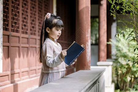 中国风女孩汉服儿童坐在公园庭院里看书背景