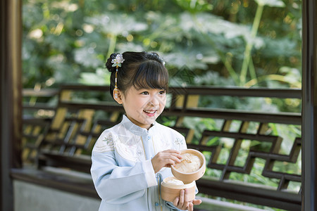 古装儿童小女孩拿蒸笼游玩公园图片