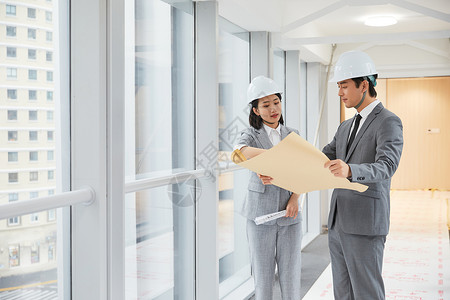 地产示意图建筑工程师拿设计图纸讨论施工项目背景