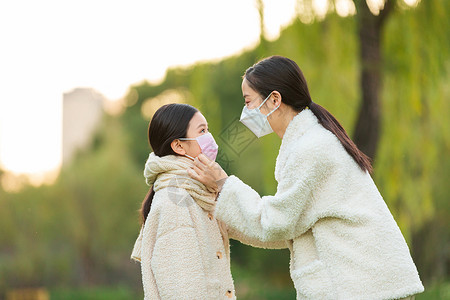 疫情防护手册公园里母亲给女儿调整口罩背景