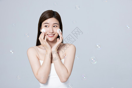 女性使用泡沫洗面奶清洁面部高清图片