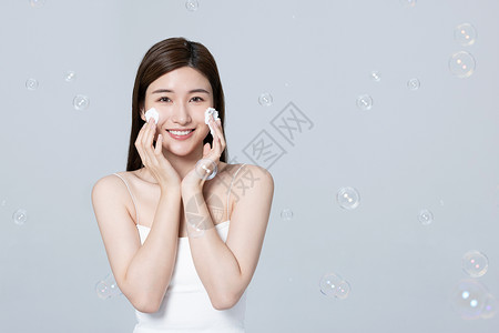 女性使用泡沫洗面奶清洗面部背景图片