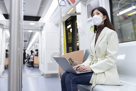 乘坐地铁的女性使用笔记本电脑图片