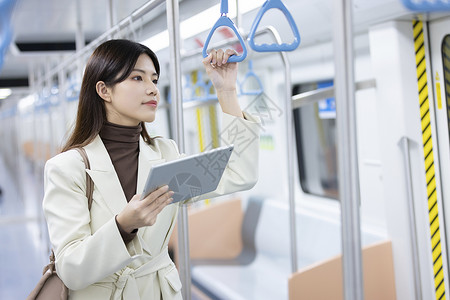 地铁上拿着平板电脑的女性背景图片