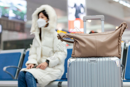 旅行存包处坐在候车厅戴着口罩等车的女性行李箱包特写背景