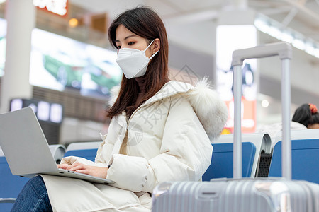 火车办公女性戴着口罩在高铁站使用笔记本电脑办公背景