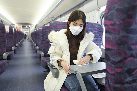 高铁口罩女性在车厢里使用消毒湿巾擦拭桌子背景