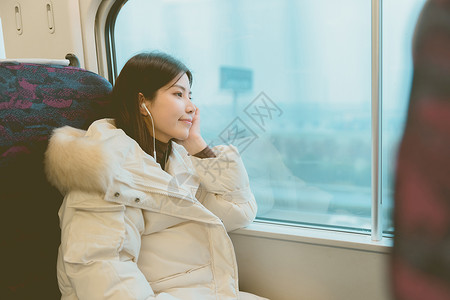 坐火车女孩坐在火车上戴着耳机看窗外风景的女性背景