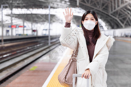 戴口罩的女性在列车站台挥手道别图片