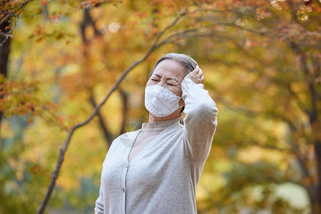 戴奎里老年人老奶奶戴口罩户外公园里头疼背景