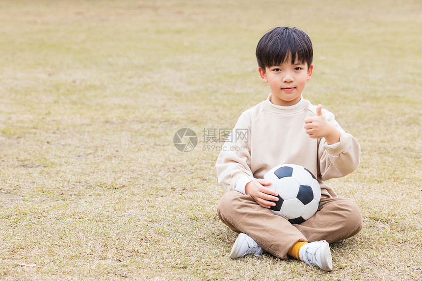 秋季小男孩公园草坪踢足球点赞图片