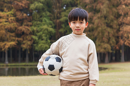 金色足球秋季小男孩公园里抱足球背景