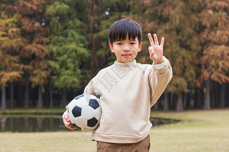 金色足球秋季小男孩公园里抱足球背景