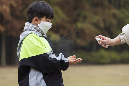 戴口罩男孩秋冬小男孩疫情期间逛公园手部消毒背景
