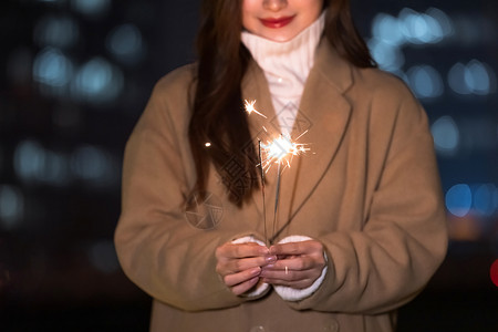 秋冬夜晚美女室外放烟花背景图片