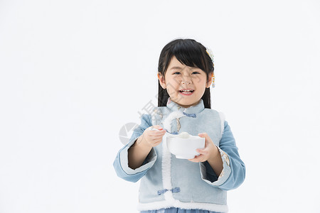 喜庆地穿着淡蓝色古装的可爱小女孩开心地吃着汤圆背景